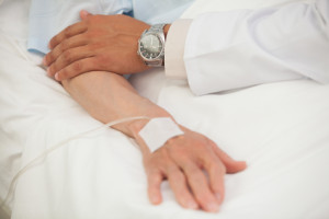 Doctor touching arm of elderly lady in hospital bed